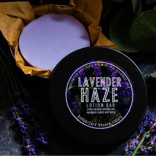 This Lavender lotion bar is shown in a black travel tin surrounded by fresh lavender.