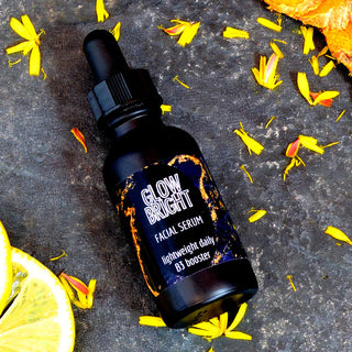 Brightening facial serum with niacinamide and hyaluronic acid in a sleek black glass dropper bottle on dark stone