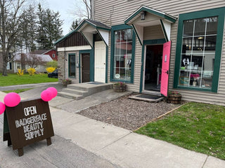 Badgerface Beauty Supply's Gilbertsville storefront is shown with an open sign and a pink front door.