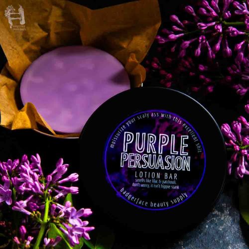 This lilac body lotion bar is shown surrounded by fresh lilacs and patchouli in a black travel tin.