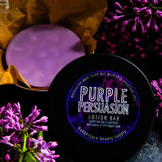 This lilac body lotion bar is shown surrounded by fresh lilacs and patchouli in a black travel tin.