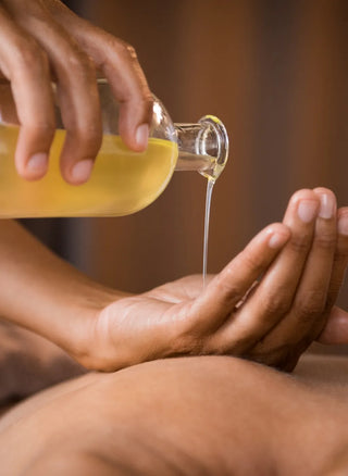 Massage oil is poured from a bottle into a hand in this close-cropped, intimate image.